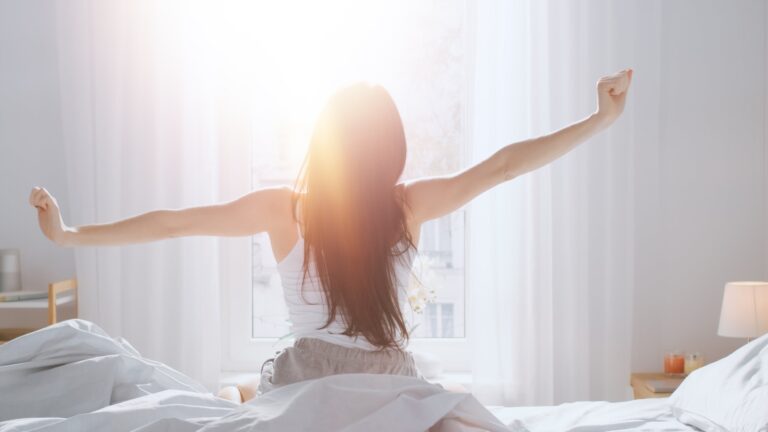 A woman stretching as she gets out of bed.