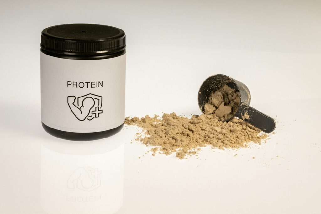 a jar of protein powder next to a scoop of protein powder