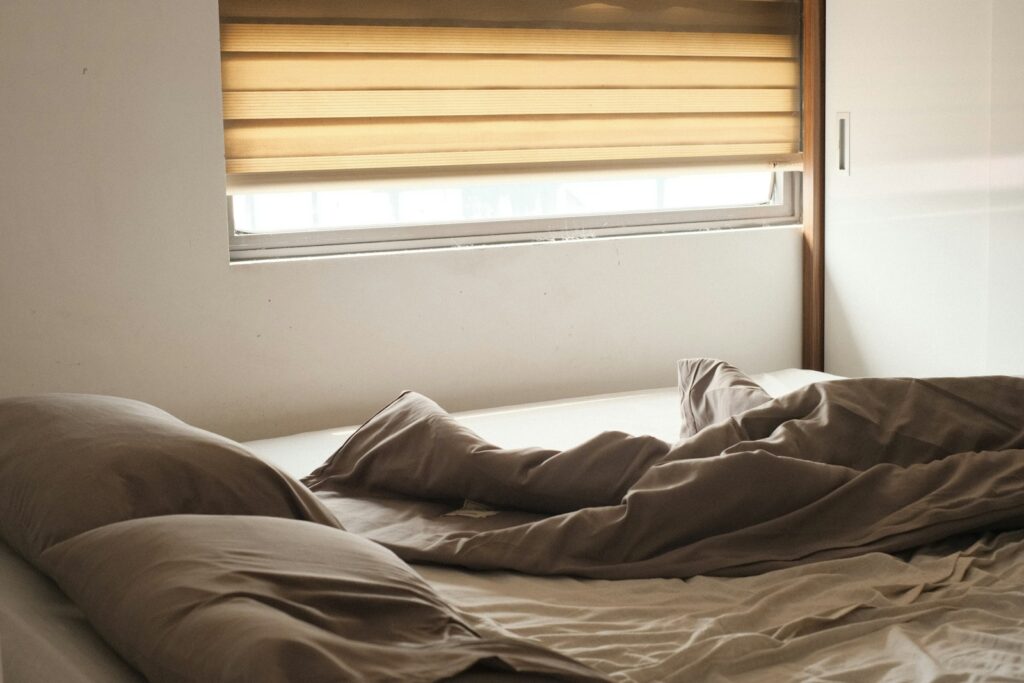a bed with a brown comforter and a window with blinds